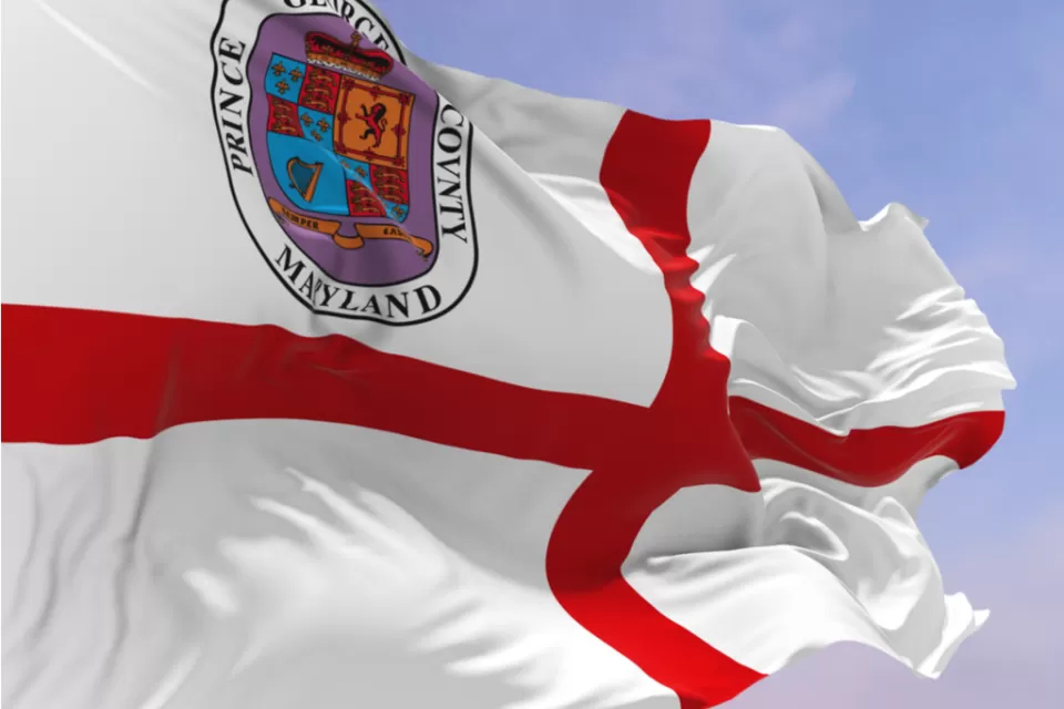 The flag of Prince George's County00a red croiss in a white field with a crest of arms in the upper left corner, blows in the wind.